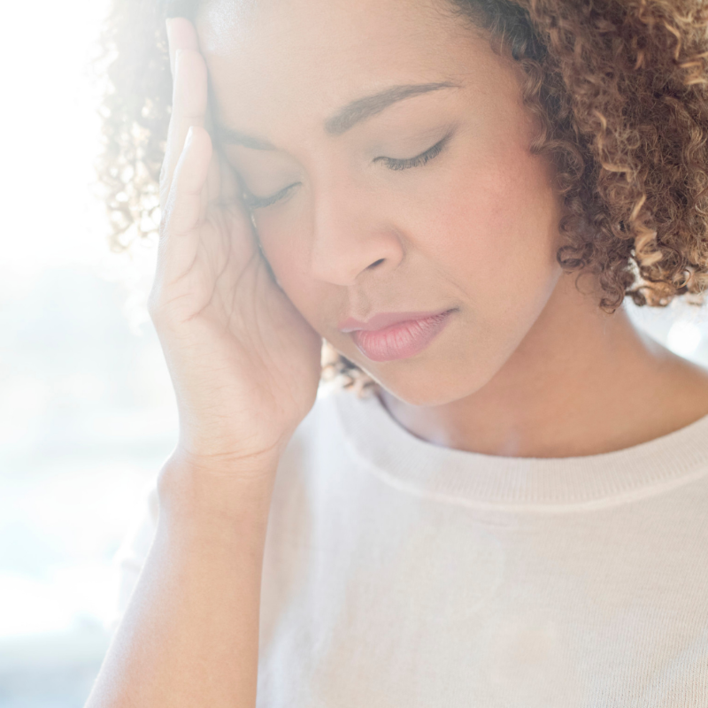 A woman with curly hair is holding her head with her hand.