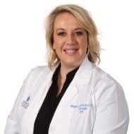A woman in a white lab coat is smiling for the camera.