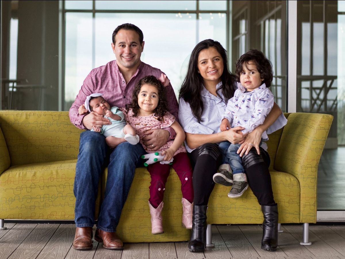 A family is posing for a picture while sitting on a yellow couch.