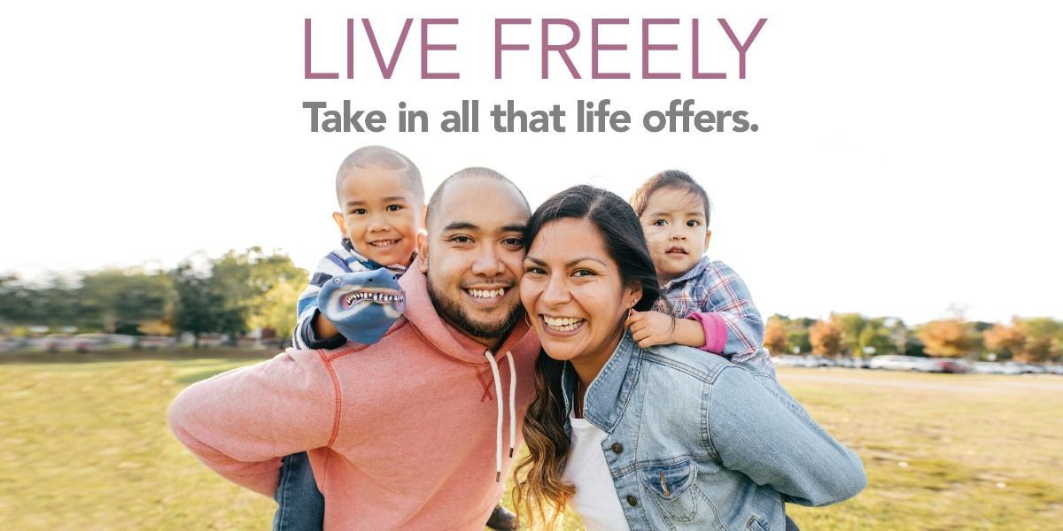 A family is standing in a field with two children on their shoulders.