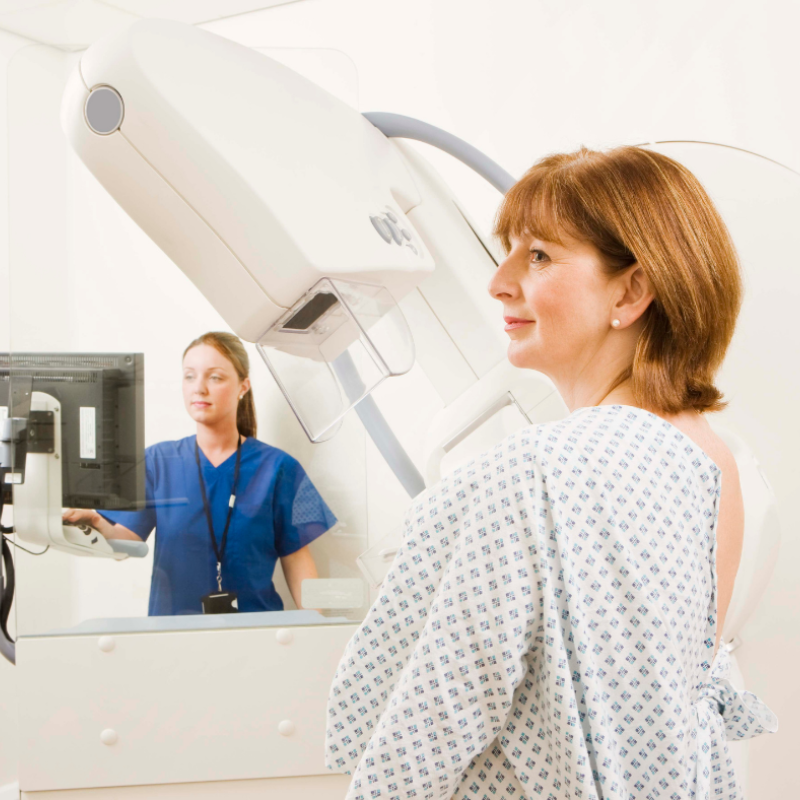 A woman in a hospital gown is getting a mammogram