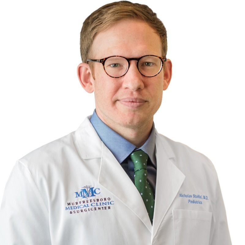 A man wearing glasses and a white coat that says mmc on it