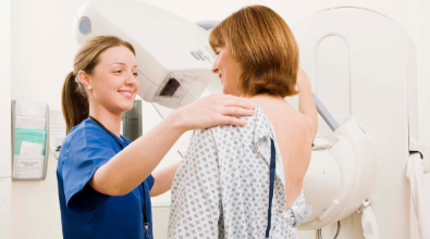 A woman is getting a mammogram from a nurse.