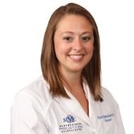 A woman in a white lab coat is smiling for the camera.