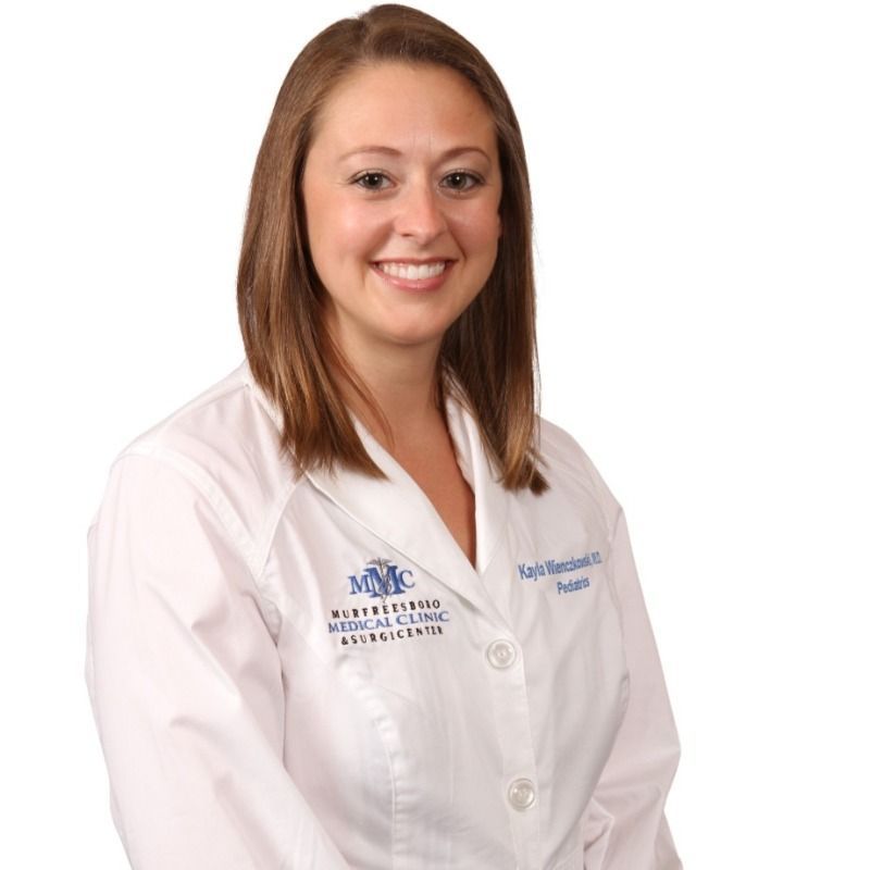 A woman wearing a white lab coat with a logo on it