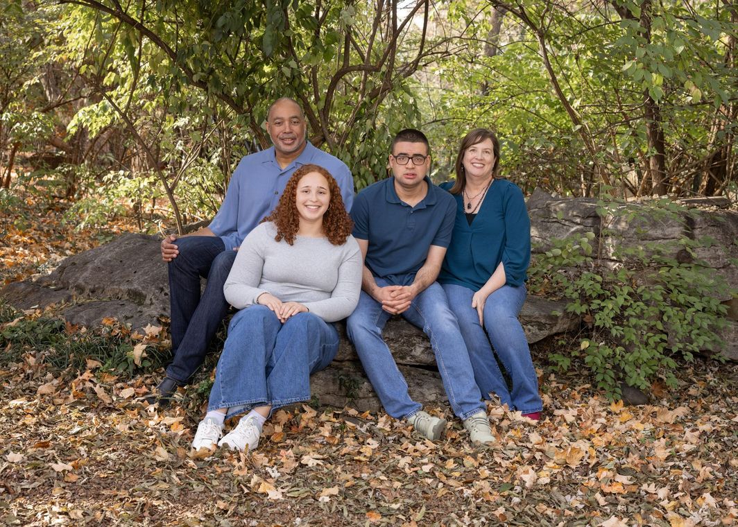 Rick with his wife and two adult children, sitting on a rock together outside. 