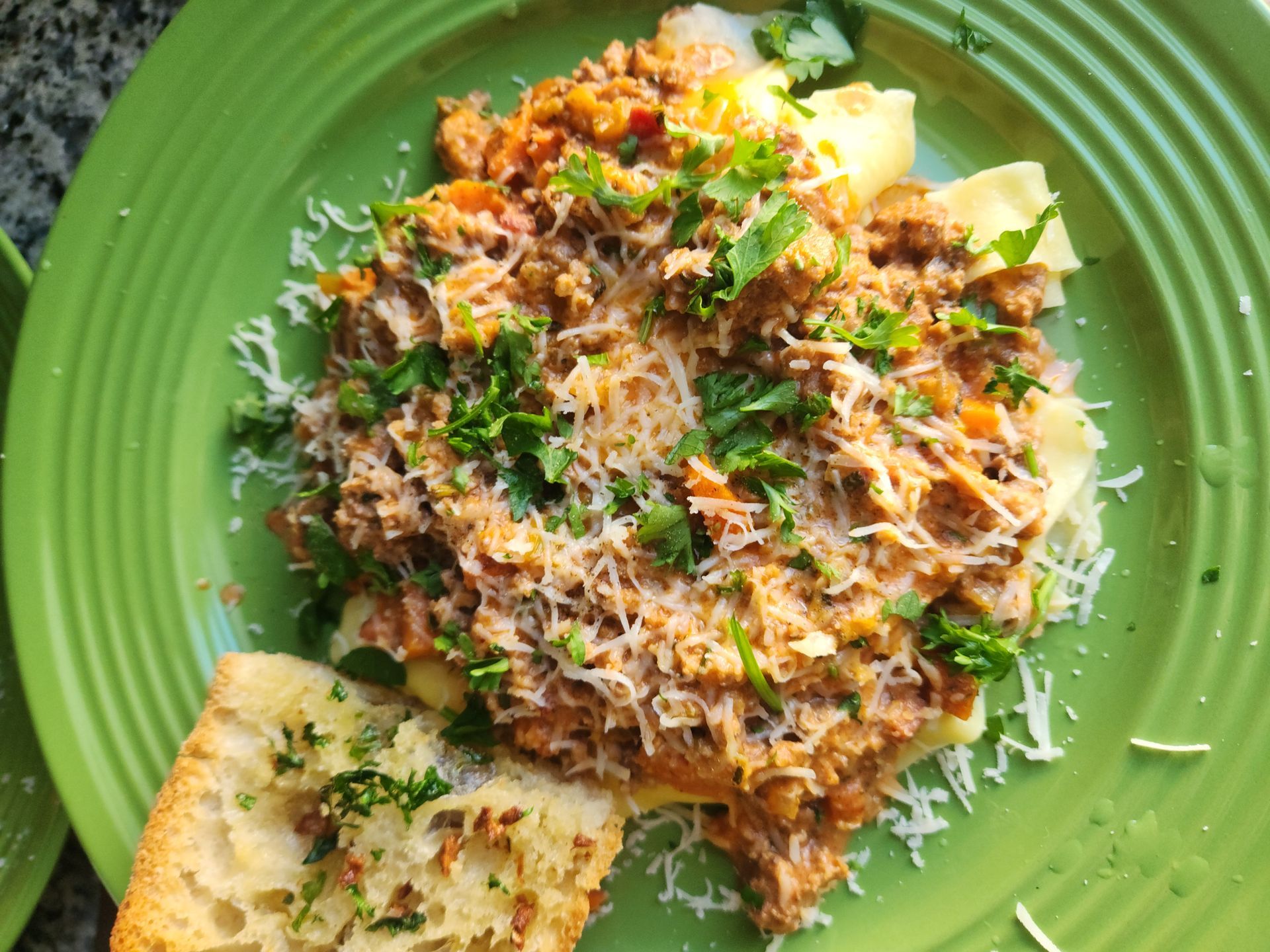 A green plate topped with meat , cheese and bread.