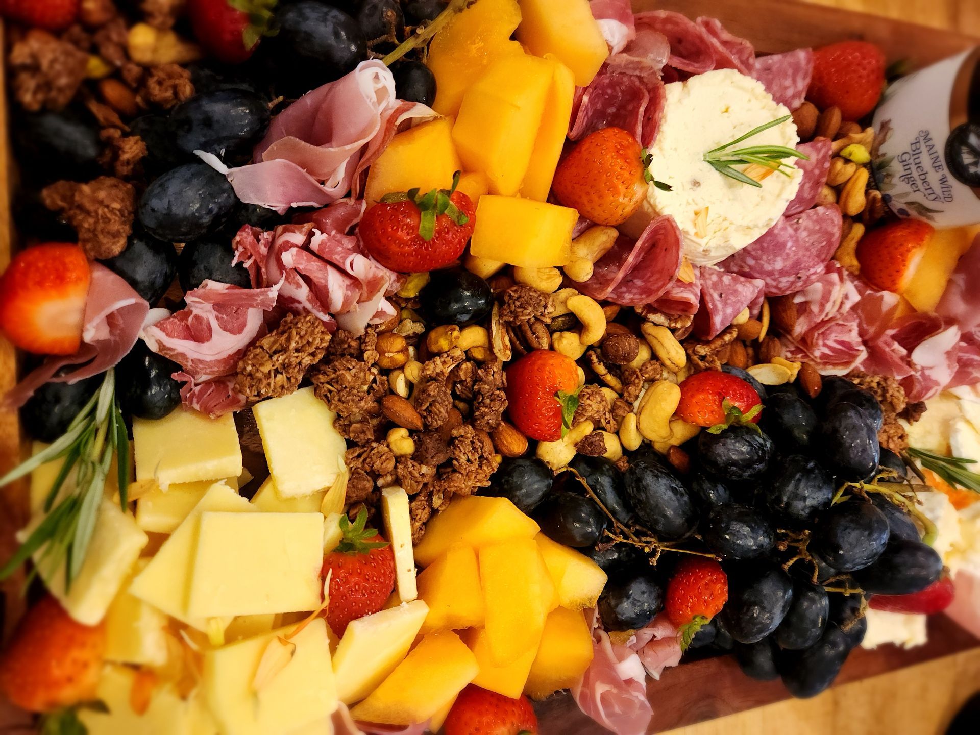 A wooden cutting board topped with a variety of fruits and meats.
