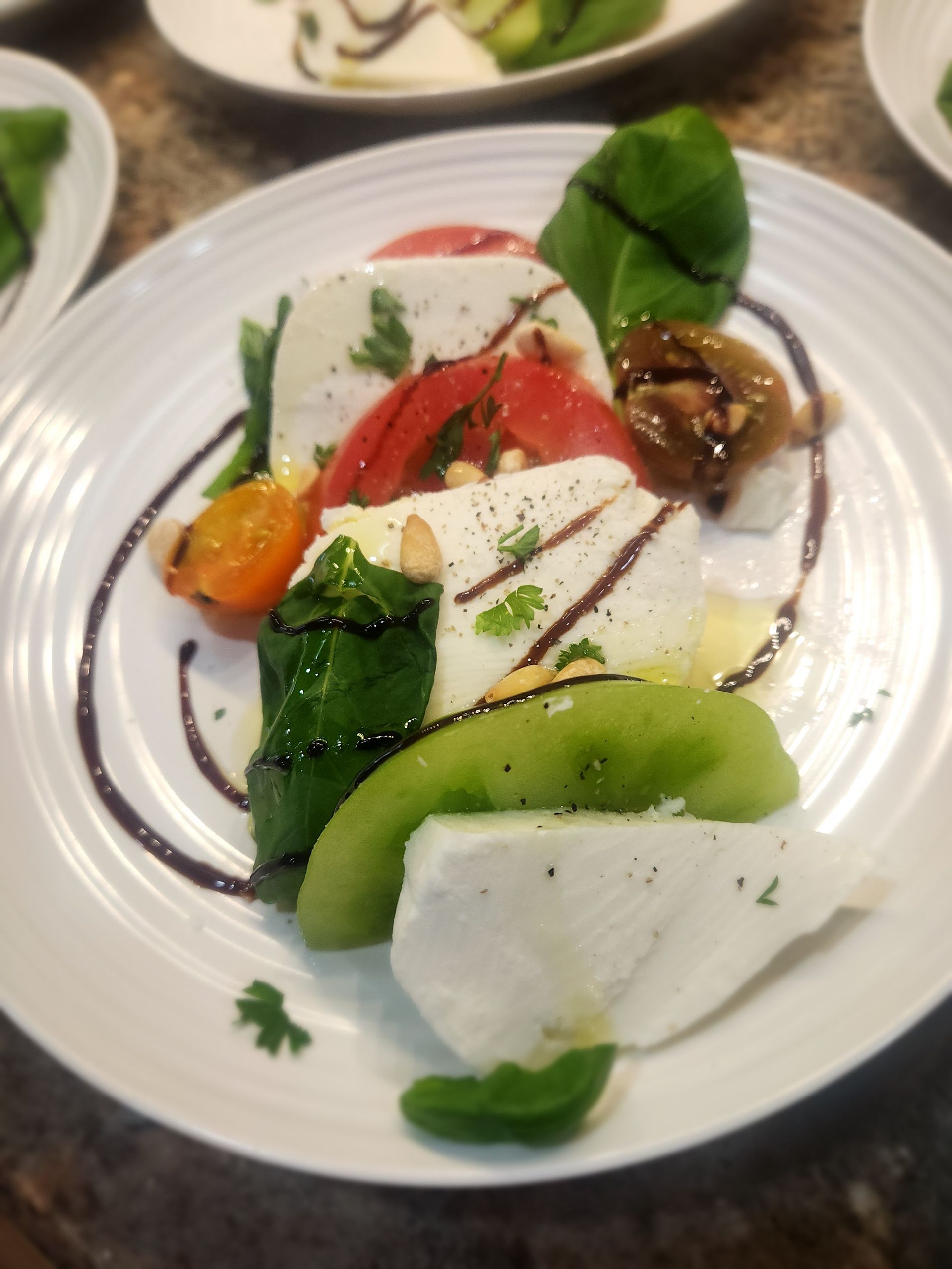 A white plate topped with a salad of vegetables and cheese