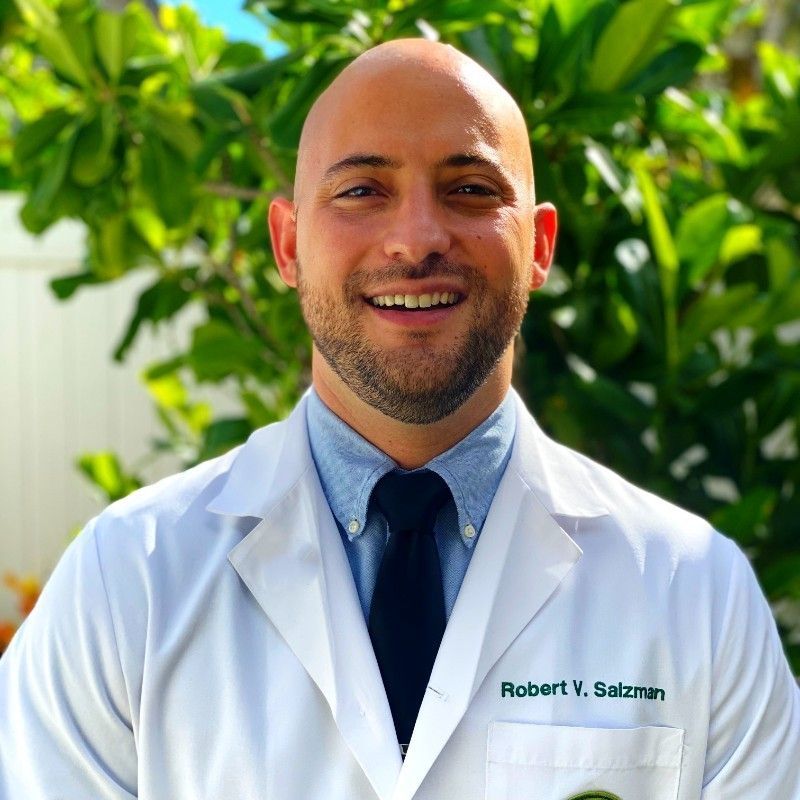 A bald man wearing a white lab coat with the name robert on it