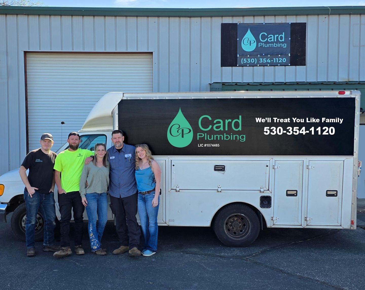 Five people posing beside a white Card Plumbing service van outside a garage
