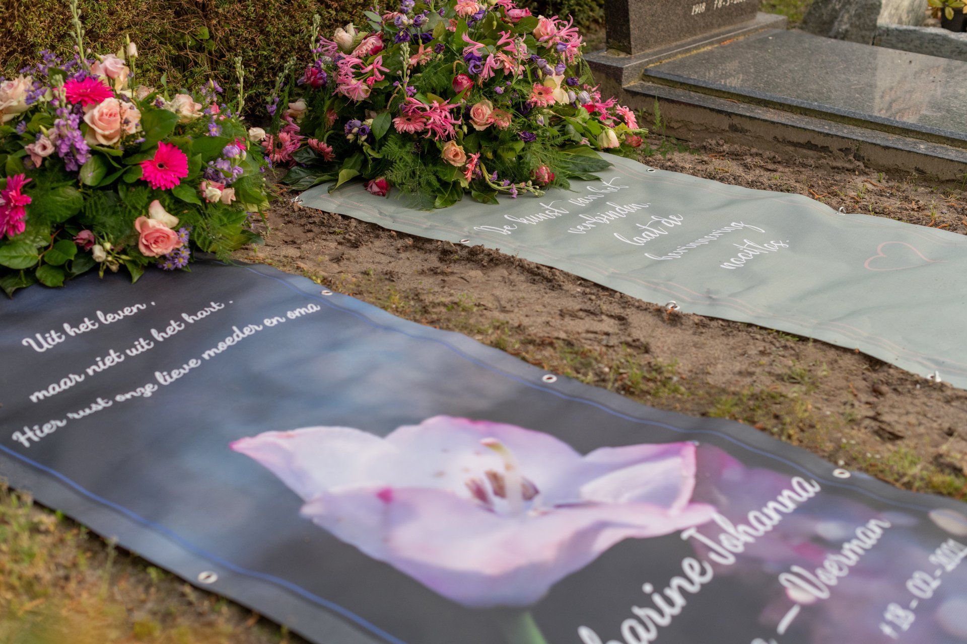 Een begraafplaats met bloemen en een spandoek met een afbeelding van een bloem erop.