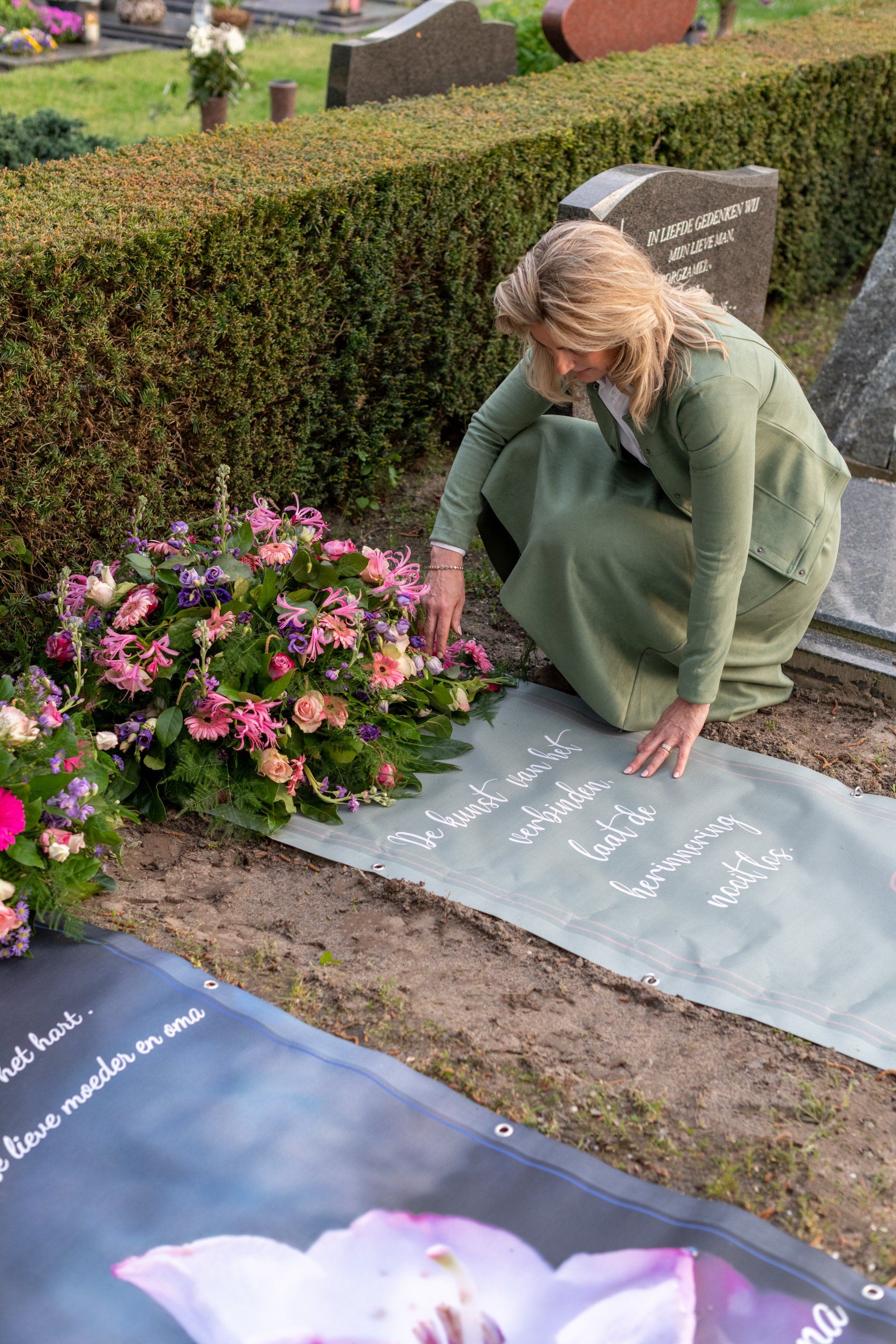 Een vrouw legt bloemen op een graf op een begraafplaats.