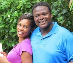 A man and a woman are posing for a picture together . the woman is holding a baby.