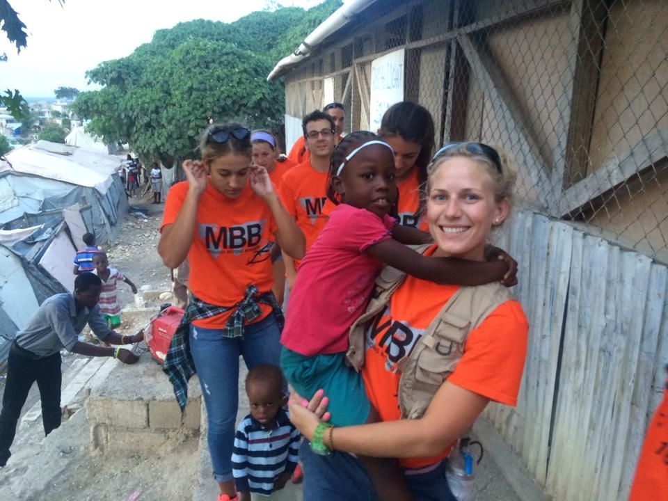 A woman holding a little girl wearing an orange mbb shirt