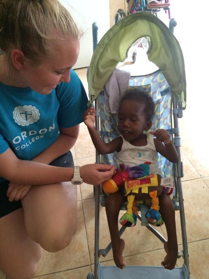 A woman in a blue shirt that says oregon is kneeling next to a baby in a stroller