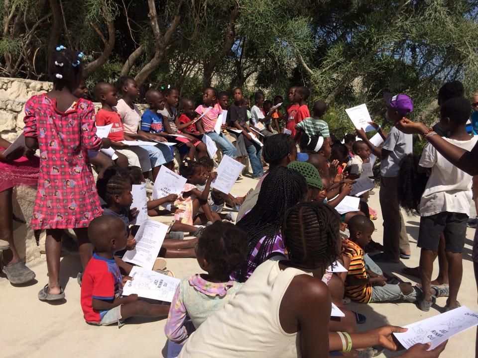 A group of people sitting on the ground holding papers