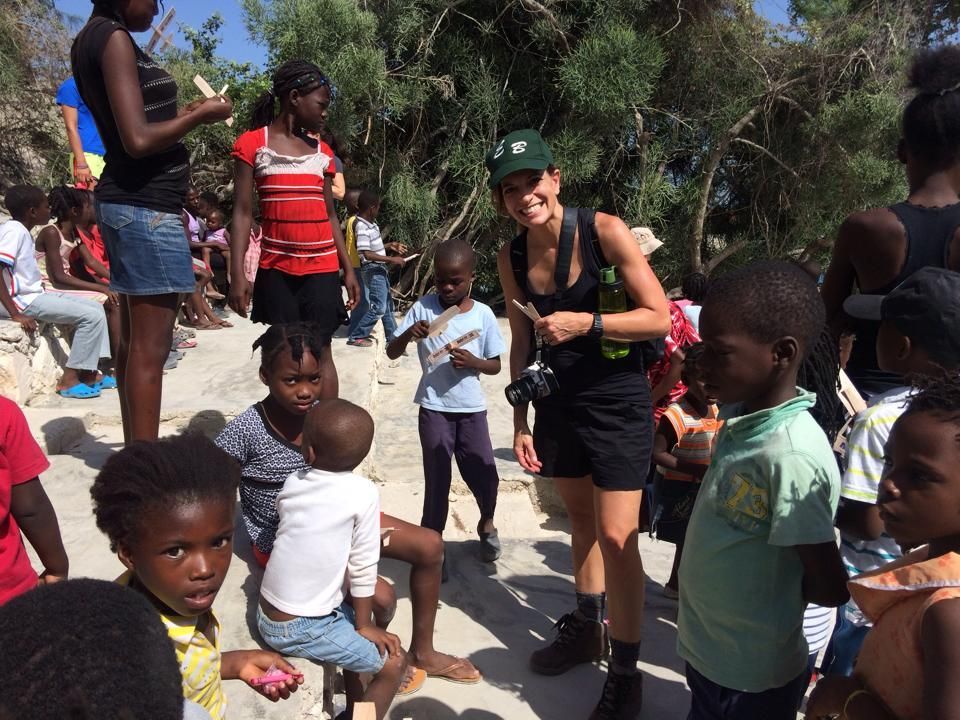 A woman is standing in a crowd of children.