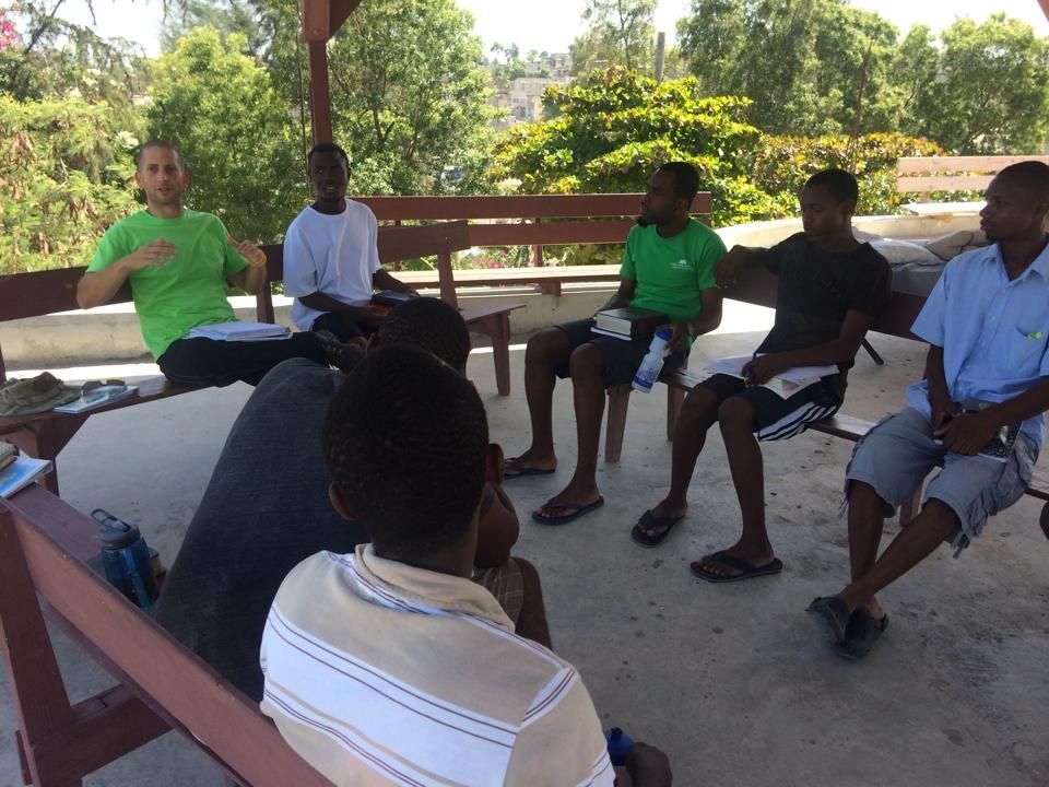 A group of men are sitting in a circle on a bench