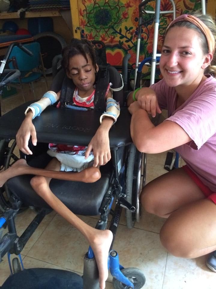 A woman is kneeling next to a child in a wheelchair.