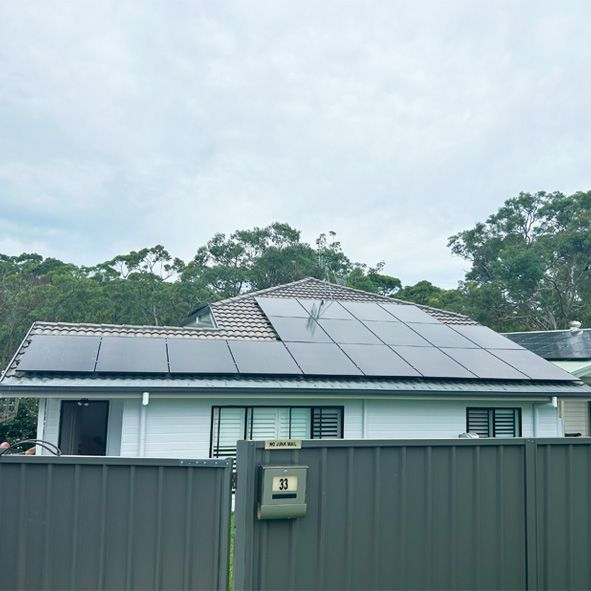 A House With a Fence and Solar Panels on the Roof — DLG Electrical and Solar In Wyong, NSW