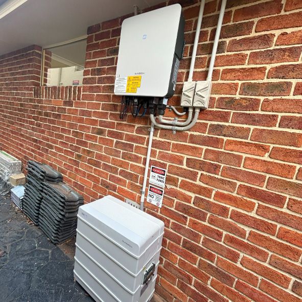 A Solar Panel is Mounted on the Side of a Brick Building — DLG Electrical and Solar In Wyong, NSW