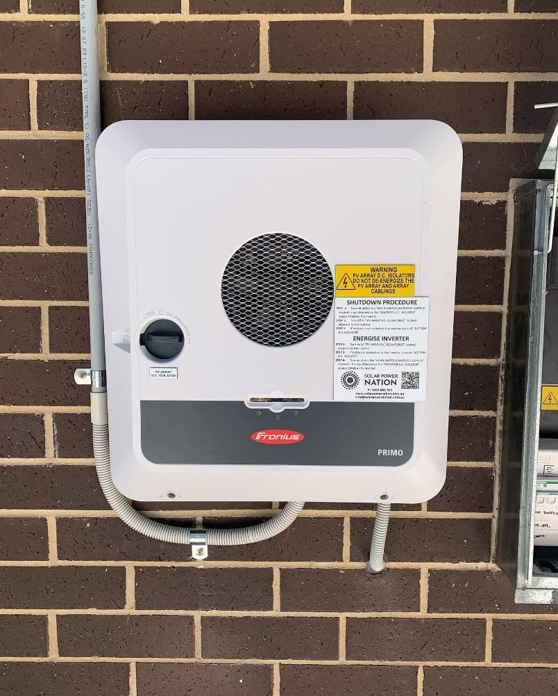 A Solar Battery is Attached to a Brick Wall — DLG Electrical and Solar In Wyong, NSW