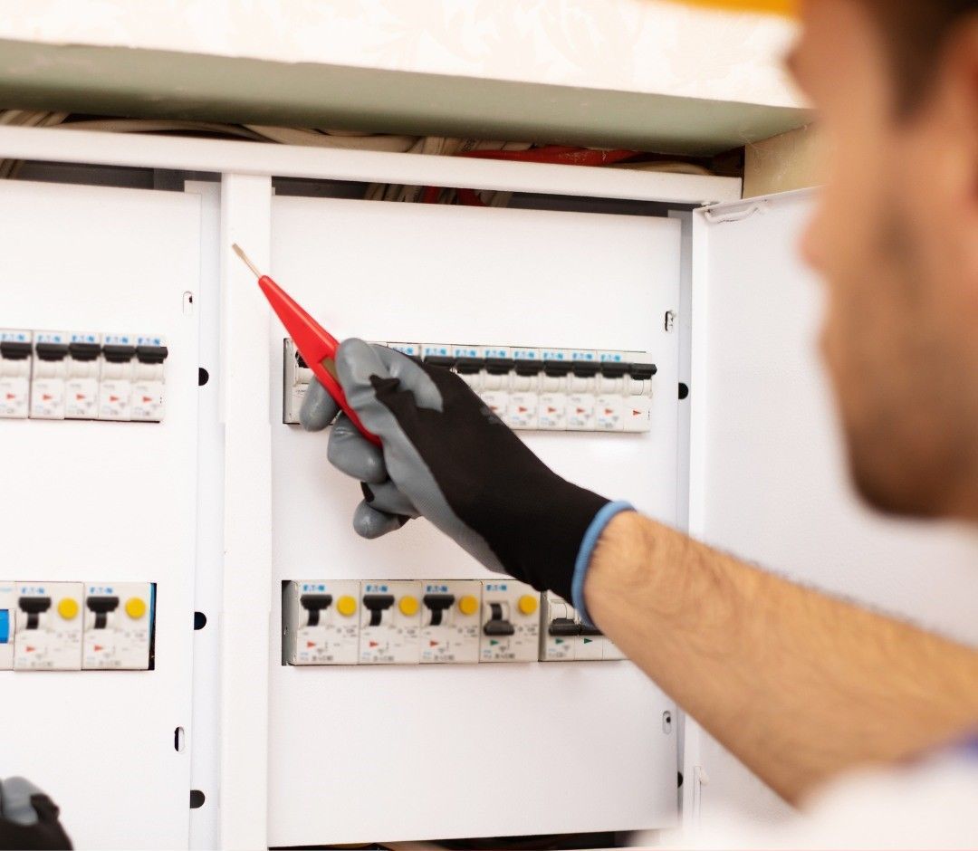 A Man is Working on an Electrical Box With a Screwdriver — DLG Electrical and Solar In Wyong, NSW