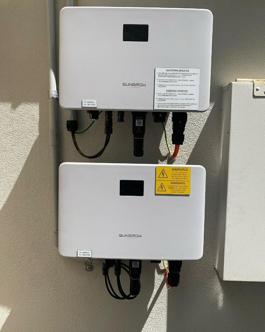 Two White Solar Inverters Are Hanging on a Wall — DLG Electrical and Solar In Newcastle, NSW