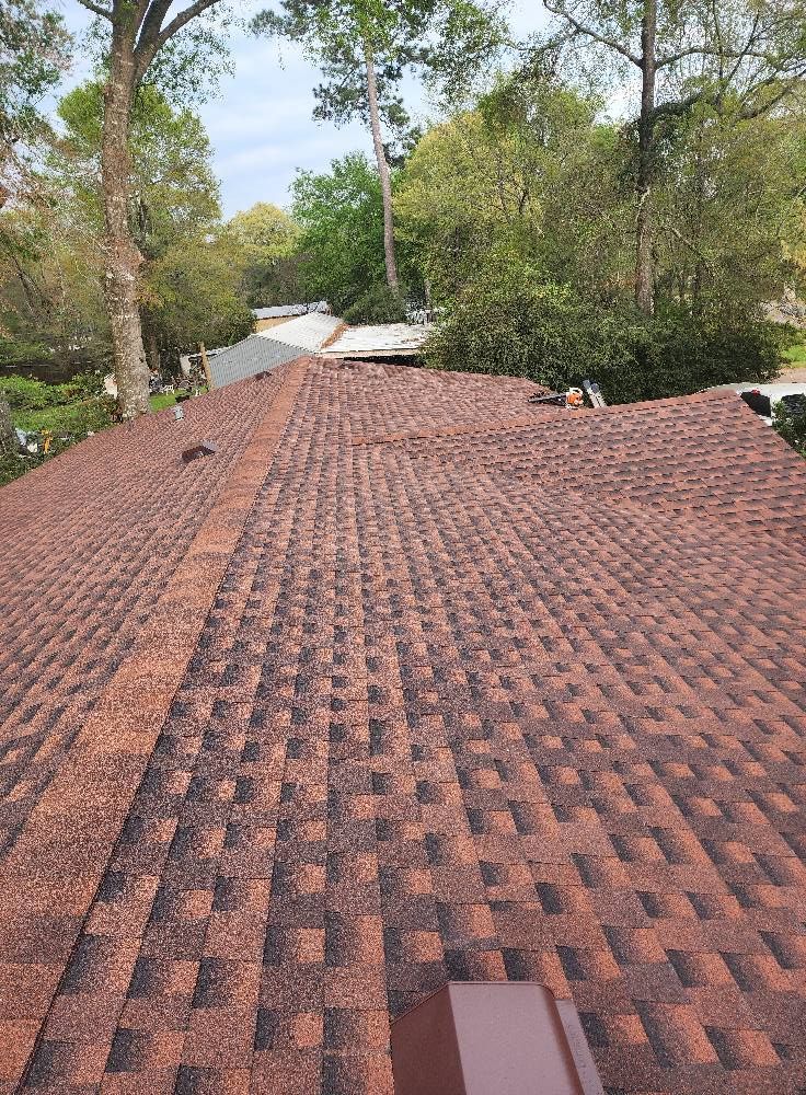 A roof with a lot of shingles on it and trees in the background.
