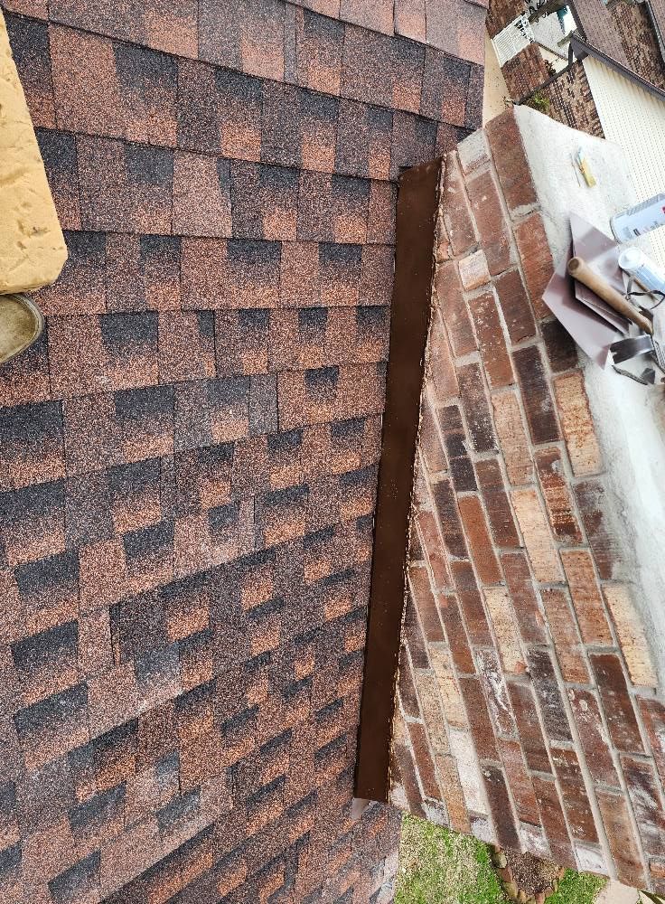 A brick wall next to a roof with shingles on it.