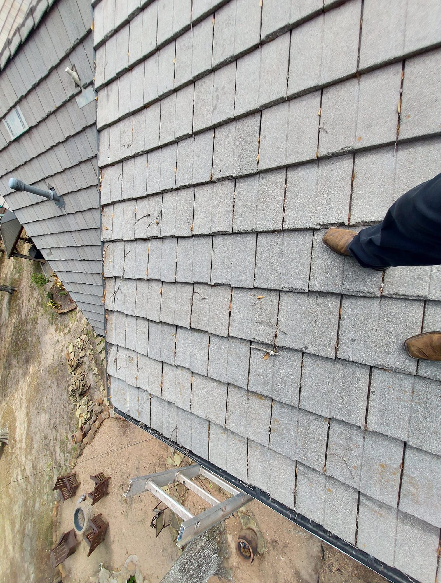 A person is standing on a brick wall with a ladder attached to it.
