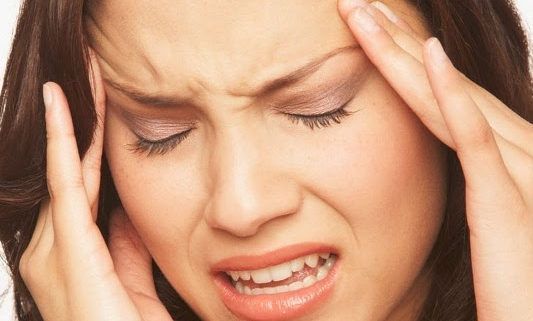A woman is holding her head in pain.