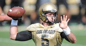 A man in a colorado football uniform is throwing a football.