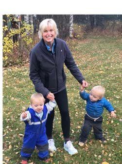 A woman is holding the hands of two babies in a field.
