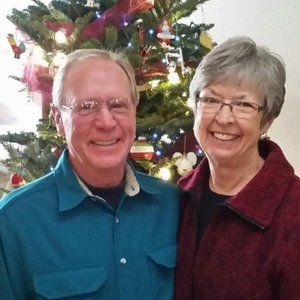 A man and a woman are posing for a picture in front of a christmas tree.
