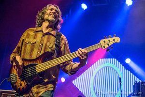 A man is playing a bass guitar on a stage.