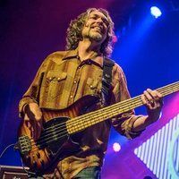 A man is playing a bass guitar on a stage.