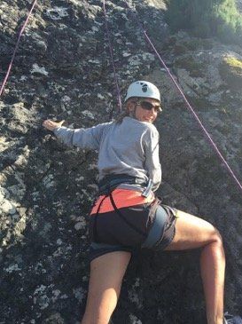 A woman is climbing a rock wall with a helmet on.