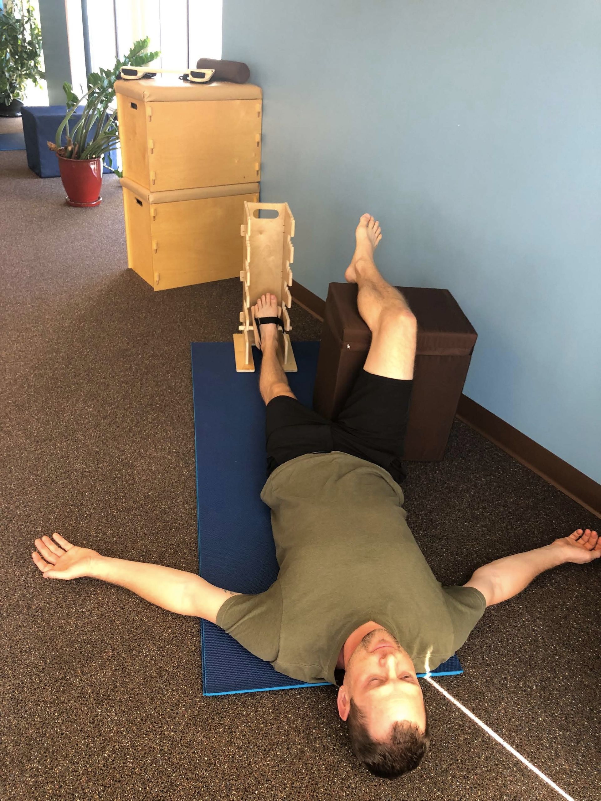 A man is laying on a blue mat with his arms outstretched
