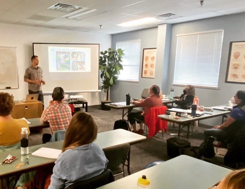 A man is giving a presentation to a group of people in a classroom.