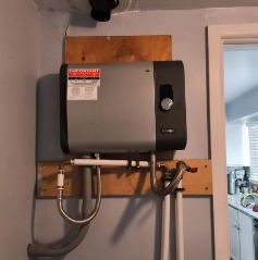 Wall-mounted tankless water heater with pipes and venting in a utility area.
