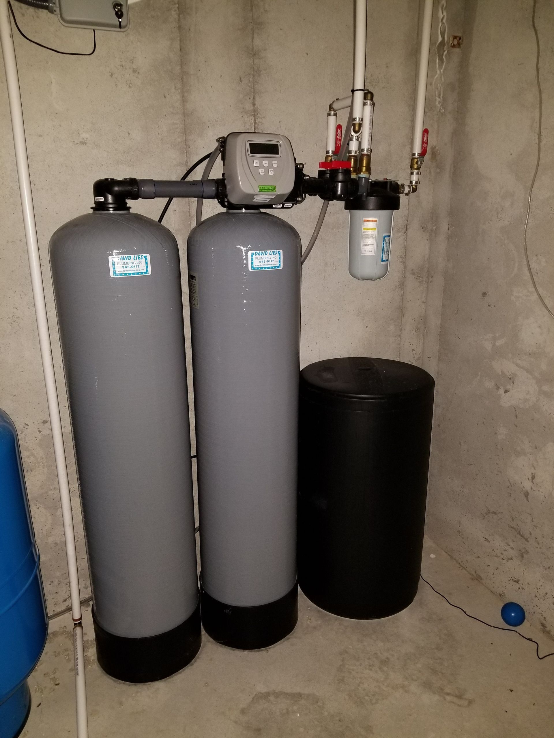 Water softener and filtration tanks in a basement utility area.