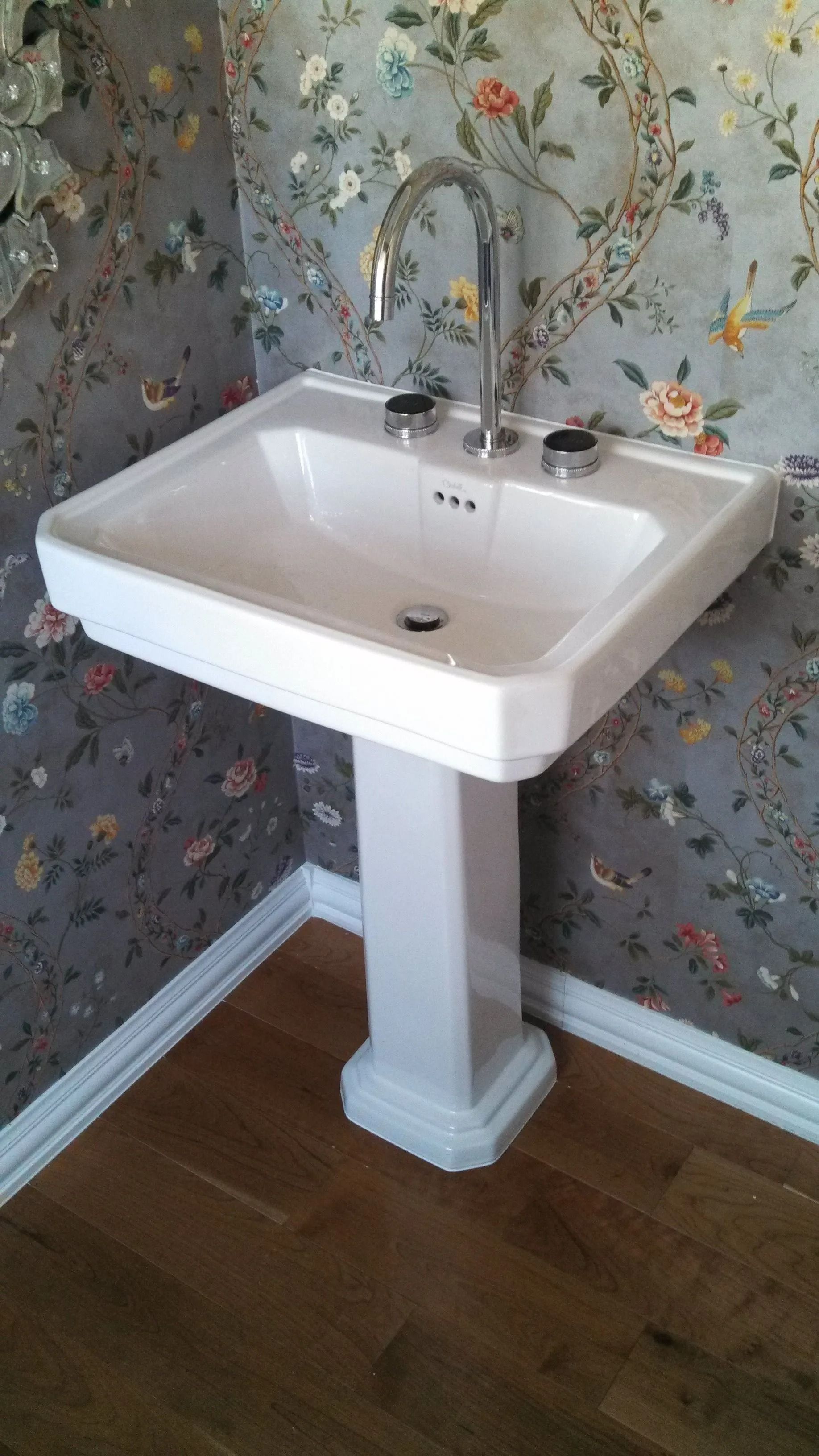 Hands installing a chrome kitchen faucet over a stainless steel sink