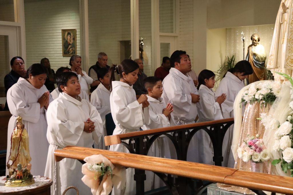 People in white robes standing in a church aisle during a solemn ceremony