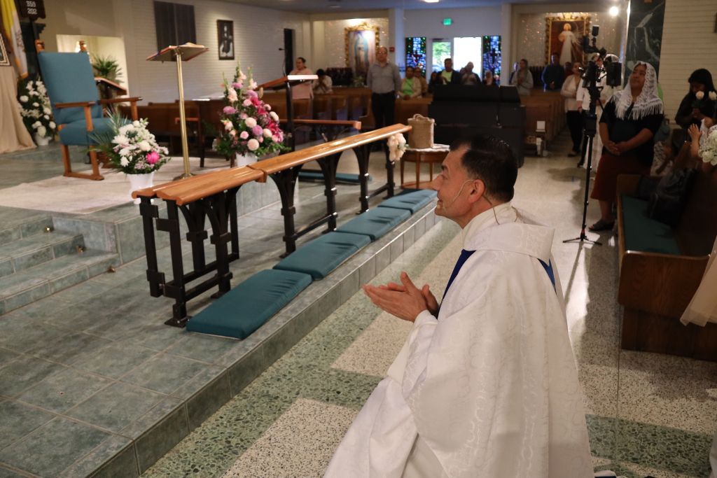 Priest kneeling in a church aisle near the altar during a service