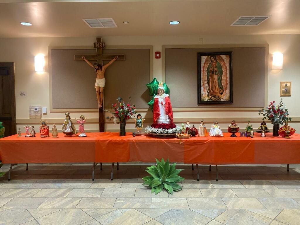 Church altar with crucifix, Guadalupe image, and orange altar cloth decorated with flowers and figurines