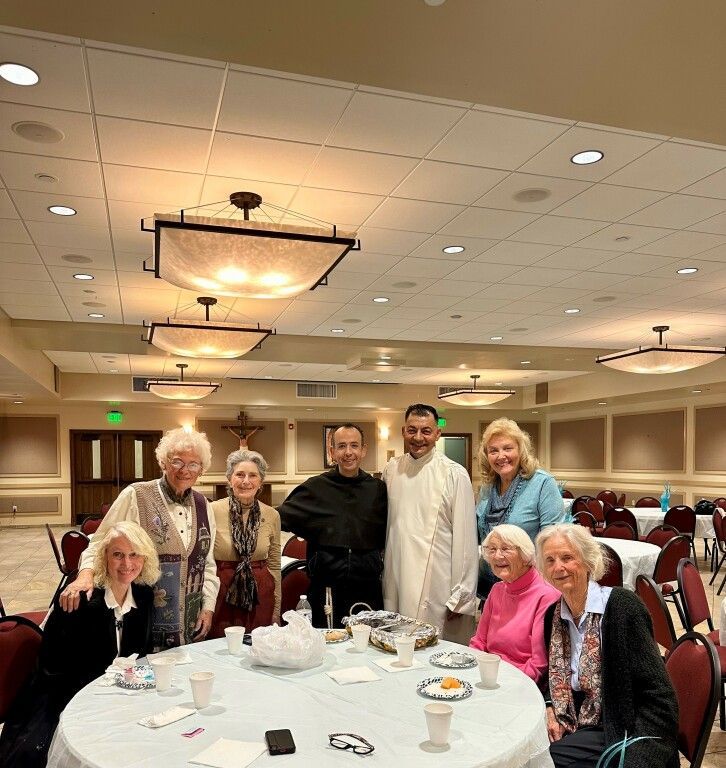 Group of people gathered around a banquet table in a conference room, smiling at the camera.