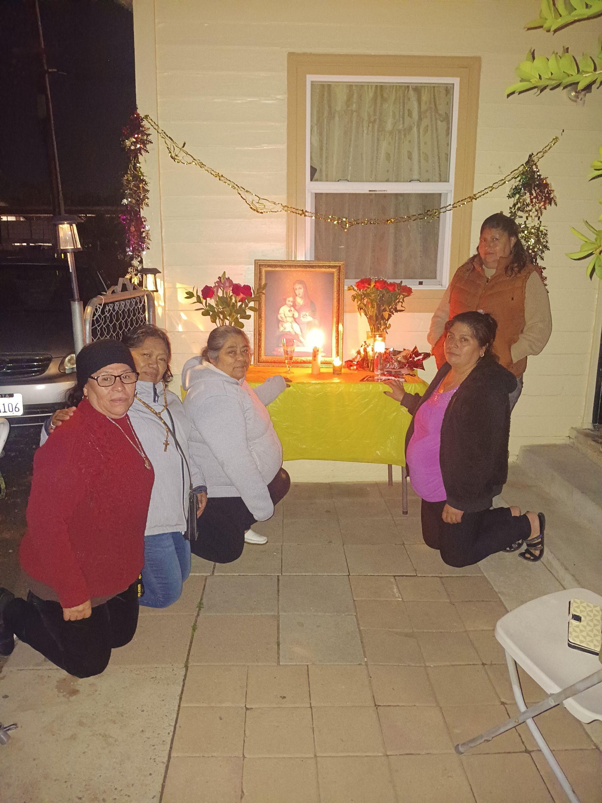 Group kneeling around a lit altar table with candles in a decorated room