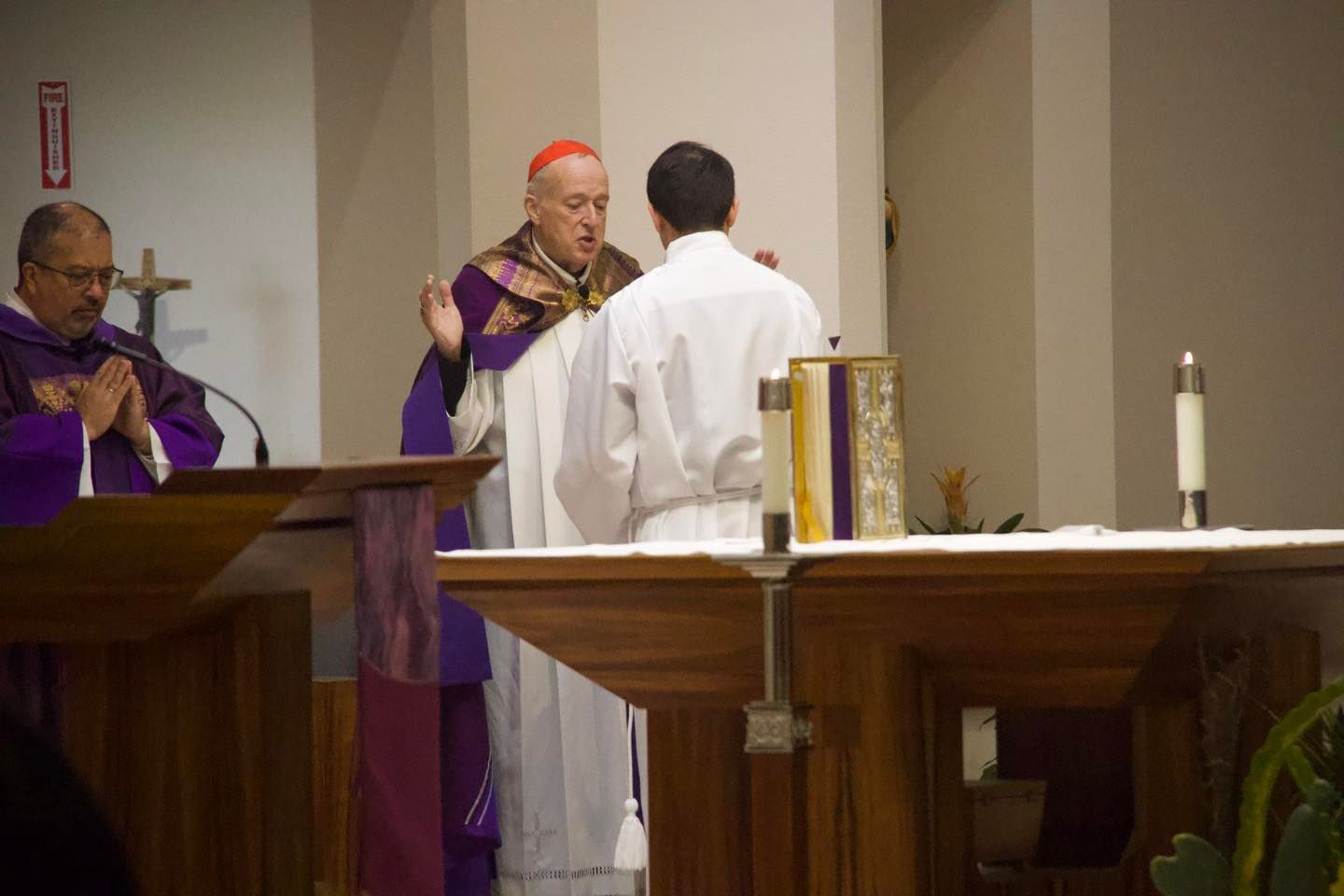 Priest in purple vestments speaking at altar during church service